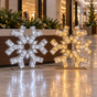 Two 3D snowflake shaped LED light decorations, one emitting a warm white light and the other a cool white light, set against a dark background.